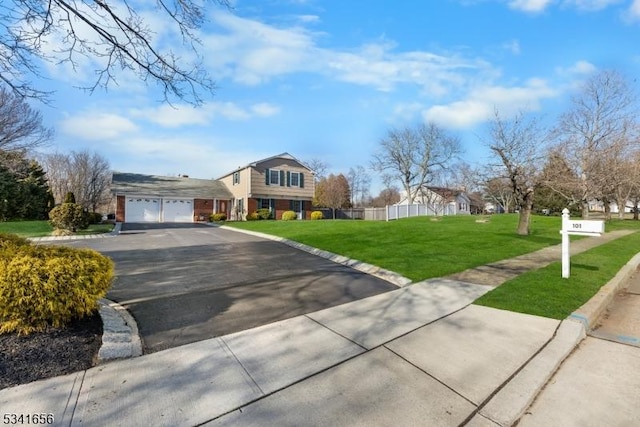 view of front of home with driveway, a front lawn, an attached garage, and fence