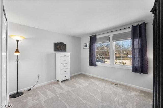 unfurnished bedroom featuring baseboards, visible vents, and light colored carpet