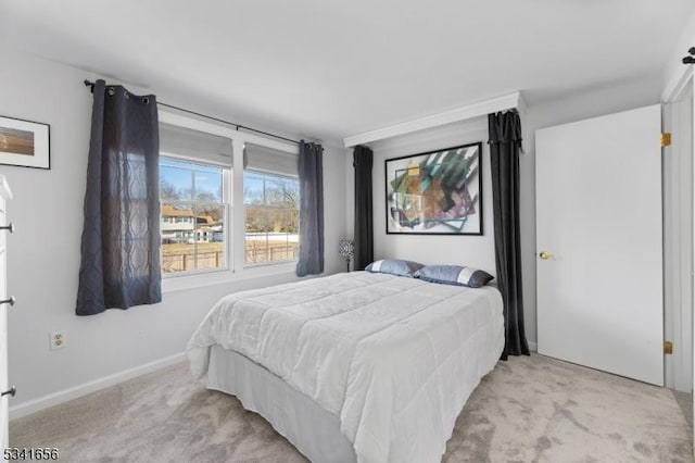 bedroom with baseboards and light colored carpet