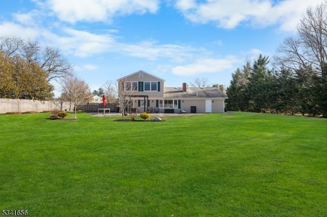 back of house featuring a yard, a patio, an attached garage, and fence