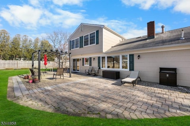 back of property with a chimney, fence, a pergola, and a patio