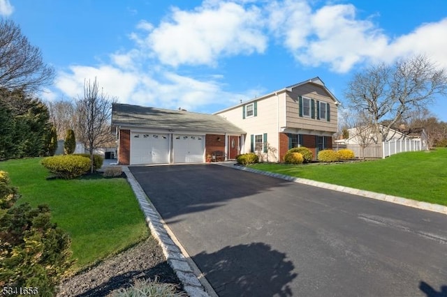 colonial inspired home featuring an attached garage, brick siding, fence, driveway, and a front lawn