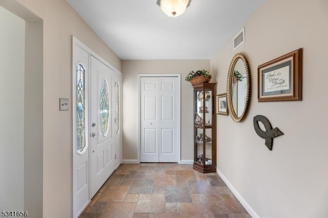 entrance foyer with stone finish floor, baseboards, and visible vents