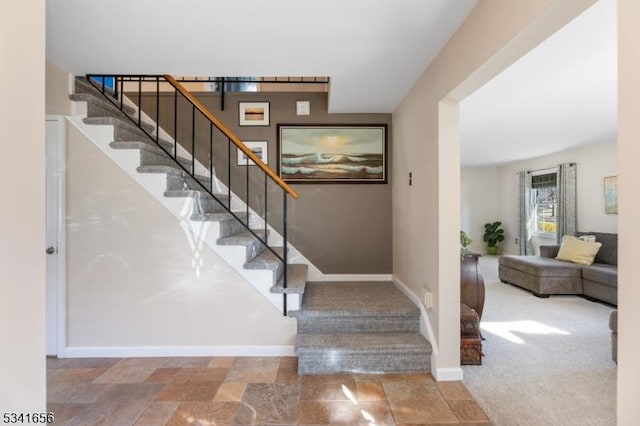 staircase featuring carpet floors, stone finish flooring, and baseboards