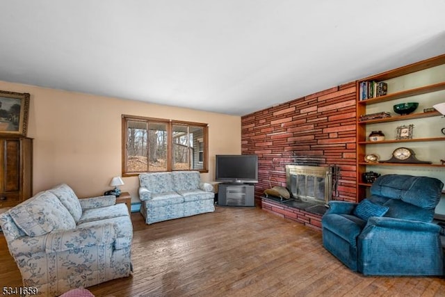 living room featuring a baseboard heating unit, a fireplace, and wood finished floors