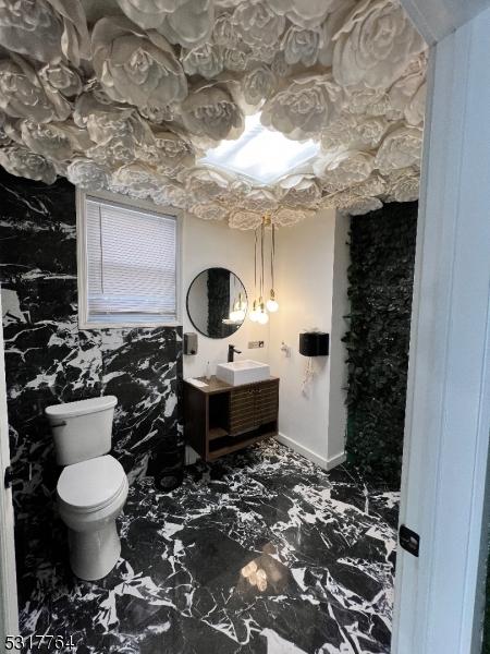 bathroom with toilet, marble finish floor, and vanity