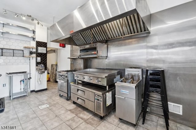 kitchen featuring open shelves, decorative backsplash, light tile patterned flooring, high end stove, and wall chimney exhaust hood