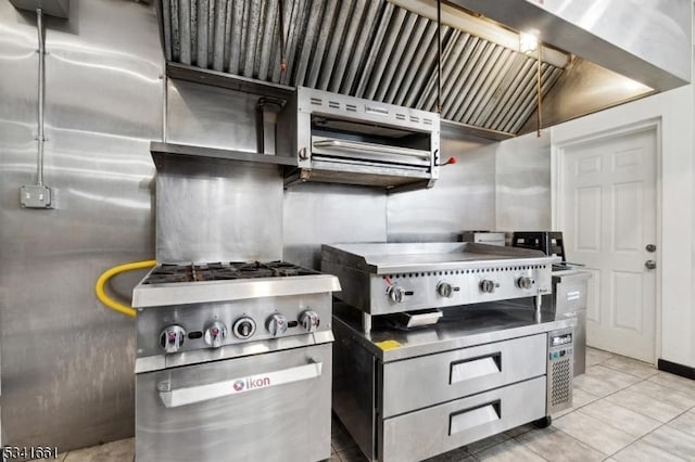 kitchen with stainless steel countertops, light tile patterned flooring, and high end stove