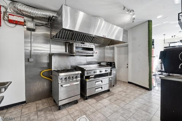 kitchen featuring light tile patterned floors, baseboards, high end stainless steel range oven, wall chimney range hood, and track lighting