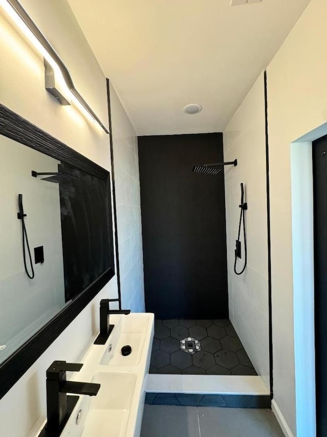 bathroom with tiled shower and a sink