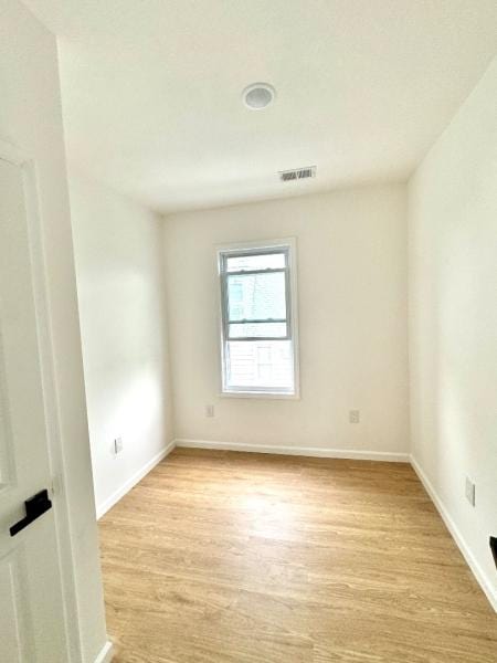 spare room featuring light wood-style flooring, visible vents, and baseboards