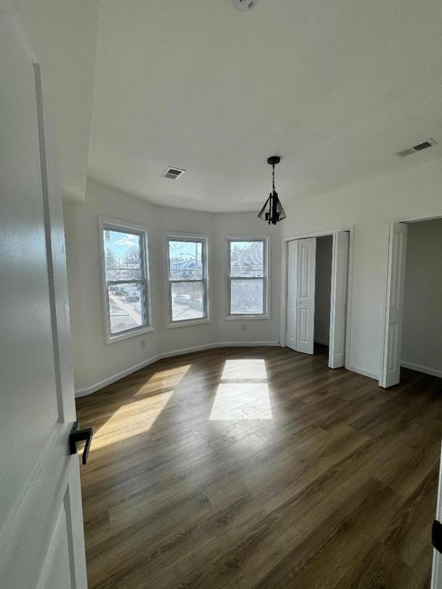 unfurnished bedroom featuring dark wood-style floors, visible vents, and multiple windows