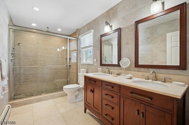 full bathroom with double vanity, a stall shower, baseboard heating, and a sink