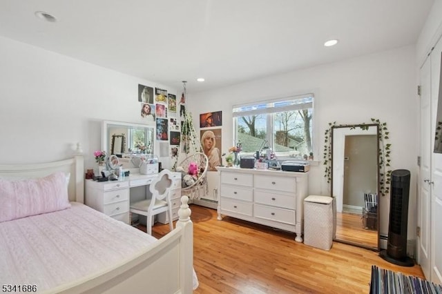 bedroom with a baseboard heating unit, light wood-style flooring, and recessed lighting