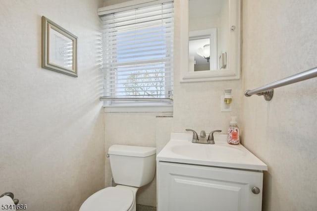 half bath featuring vanity and toilet