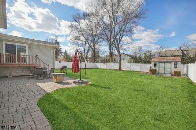 view of yard featuring an outbuilding, a patio, an outdoor fire pit, a fenced backyard, and a storage unit