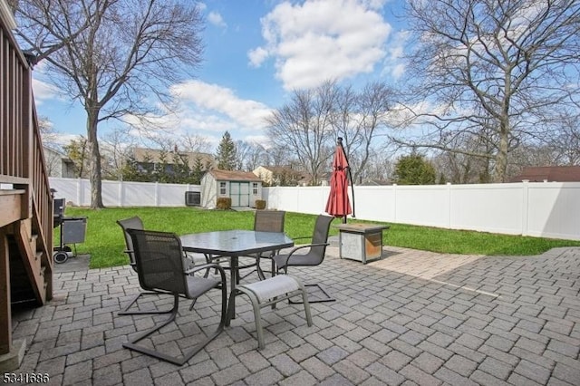 view of patio / terrace featuring a shed, an outdoor structure, a fenced backyard, and outdoor dining space