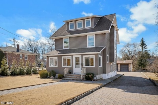 traditional style home featuring a garage, an outdoor structure, driveway, and a shingled roof