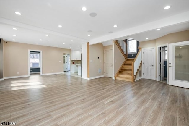 unfurnished living room with light wood-type flooring, stairway, and recessed lighting