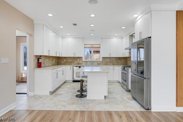 kitchen with light countertops, appliances with stainless steel finishes, a breakfast bar area, and white cabinets