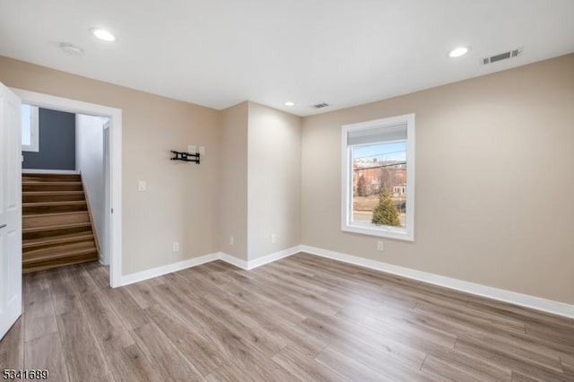 unfurnished room featuring stairs, baseboards, visible vents, and light wood-style floors