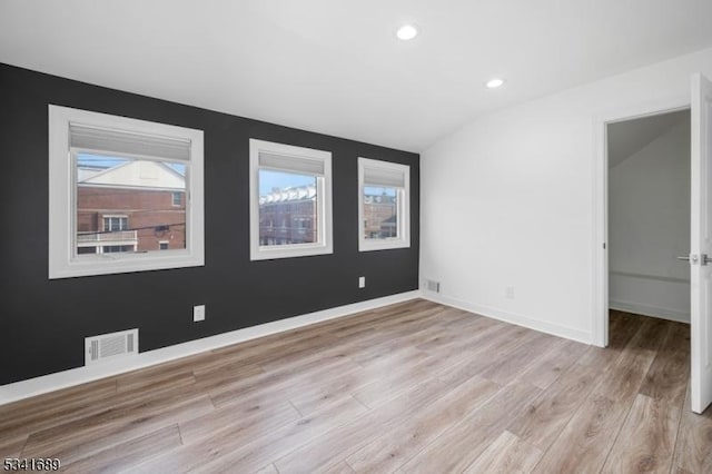 empty room with recessed lighting, visible vents, baseboards, vaulted ceiling, and light wood-style floors