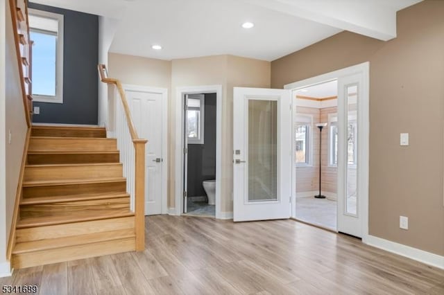 foyer entrance with stairway, a healthy amount of sunlight, light wood-style flooring, and baseboards