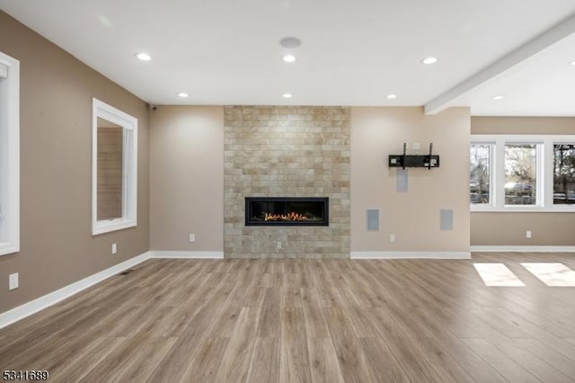 unfurnished living room featuring light wood-style floors, a fireplace, baseboards, and recessed lighting