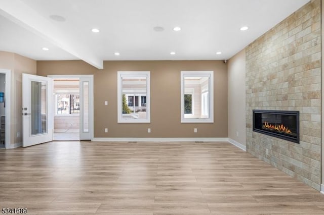 unfurnished living room featuring recessed lighting, light wood-style flooring, baseboards, and a tile fireplace