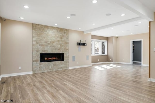 unfurnished living room with light wood finished floors, baseboards, and a tiled fireplace