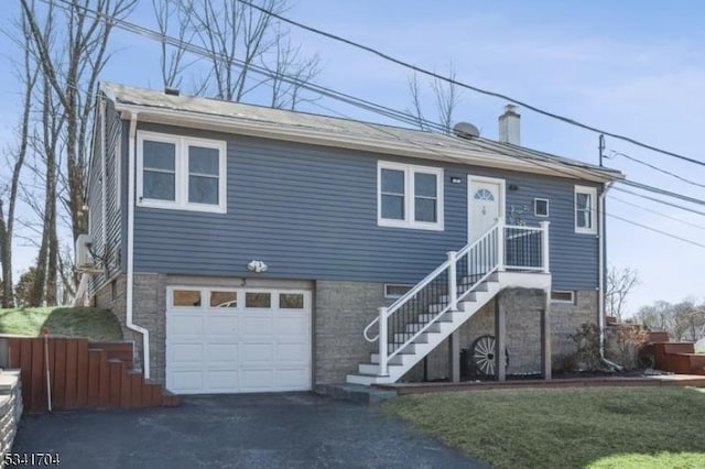 view of front facade featuring aphalt driveway, a chimney, an attached garage, and fence