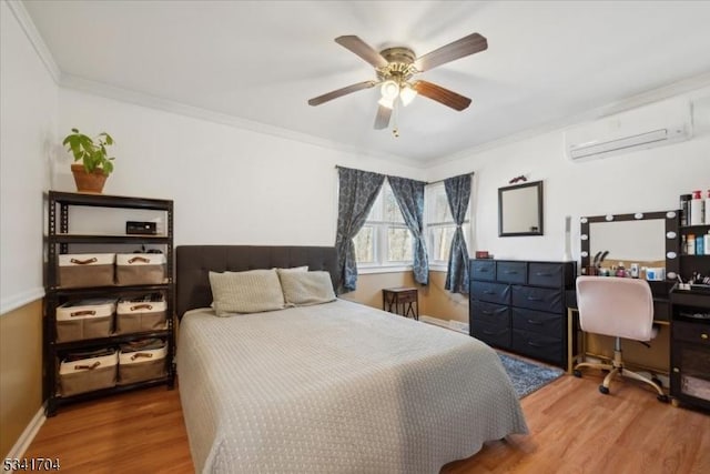 bedroom with ornamental molding, an AC wall unit, ceiling fan, wood finished floors, and baseboards