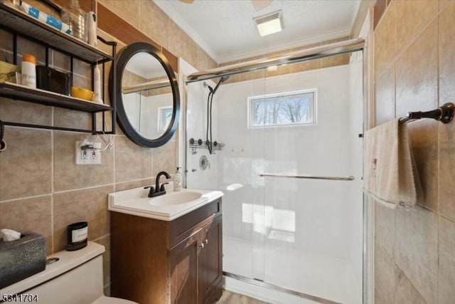 full bathroom with toilet, vanity, tile walls, ornamental molding, and a shower stall