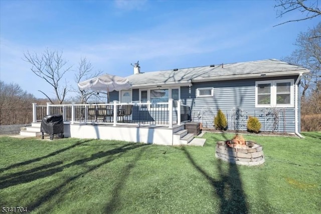 rear view of house with a fire pit, a yard, and a deck