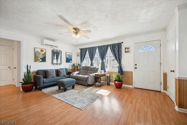 living room with a textured ceiling, a wall unit AC, and wood finished floors