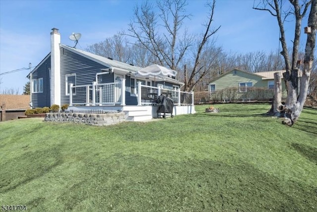 exterior space featuring a lawn, a chimney, and a wooden deck