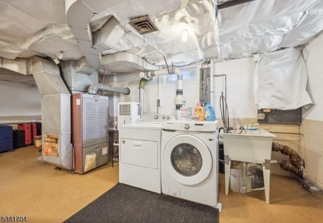 laundry area with heating unit, visible vents, a sink, separate washer and dryer, and laundry area