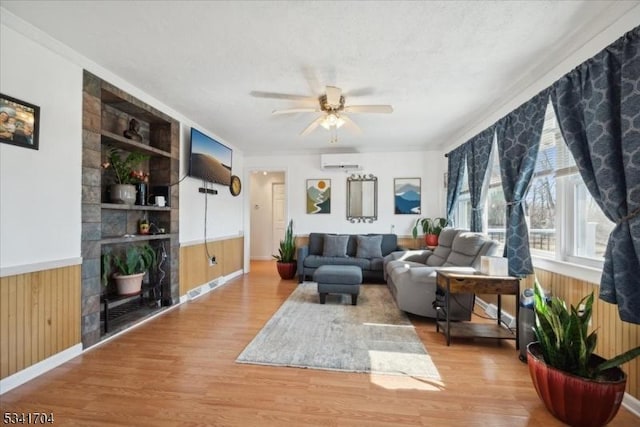 living area with a wainscoted wall, wood walls, a wall mounted AC, and wood finished floors