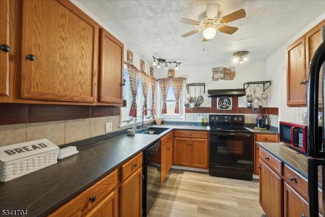 kitchen featuring brown cabinetry, dark countertops, a textured ceiling, black appliances, and a sink