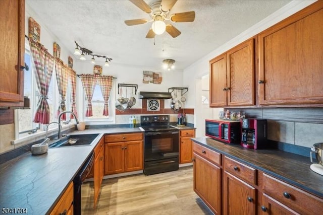 kitchen with brown cabinetry, a sink, a textured ceiling, light wood-type flooring, and black appliances