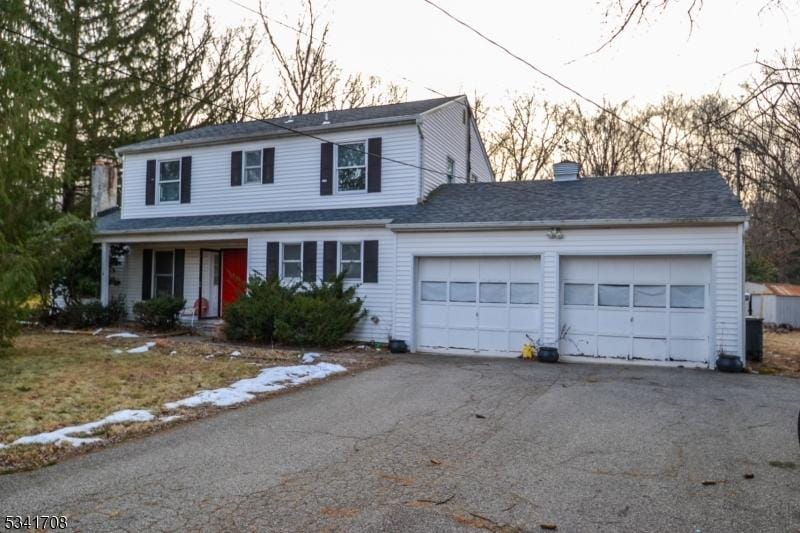 traditional home featuring driveway, a chimney, and an attached garage