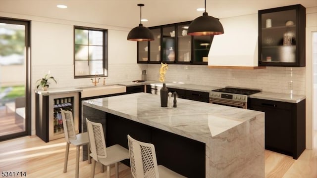 kitchen featuring wall chimney exhaust hood, beverage cooler, decorative backsplash, and stainless steel range with gas stovetop