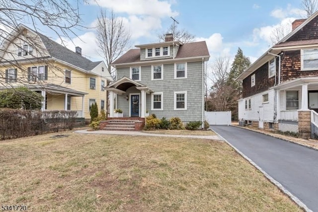 traditional style home featuring a front yard, driveway, and a chimney