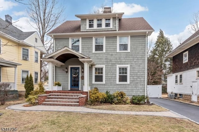 american foursquare style home with a shingled roof, cooling unit, driveway, and a chimney