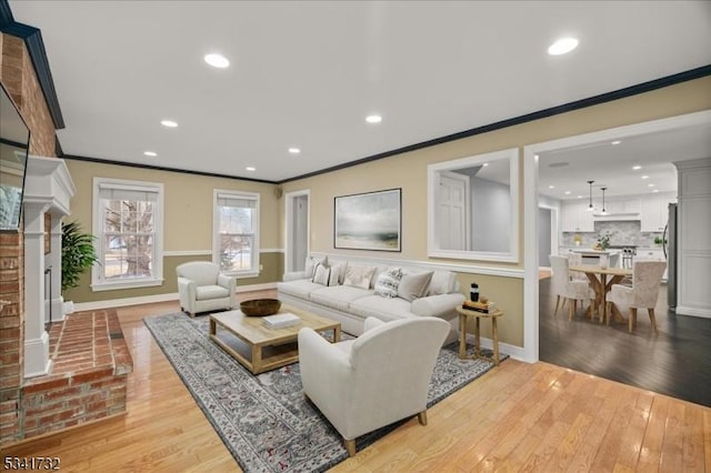 living area with ornamental molding, recessed lighting, and light wood-style floors