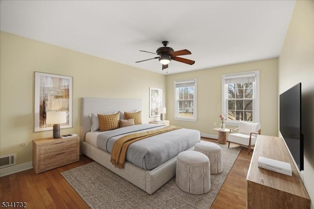 bedroom with baseboards, visible vents, ceiling fan, and wood finished floors