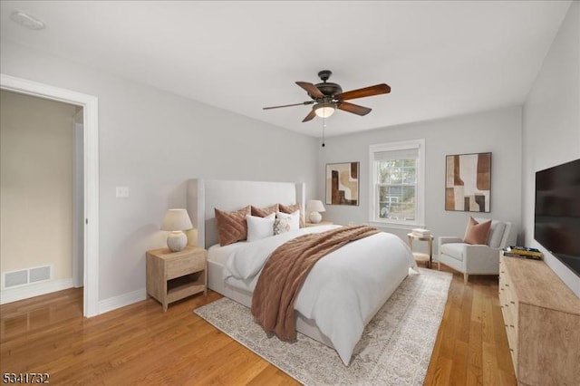 bedroom featuring baseboards, ceiling fan, visible vents, and light wood-style floors