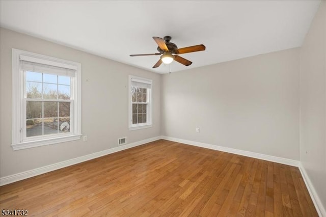 unfurnished room featuring light wood finished floors, baseboards, visible vents, and ceiling fan