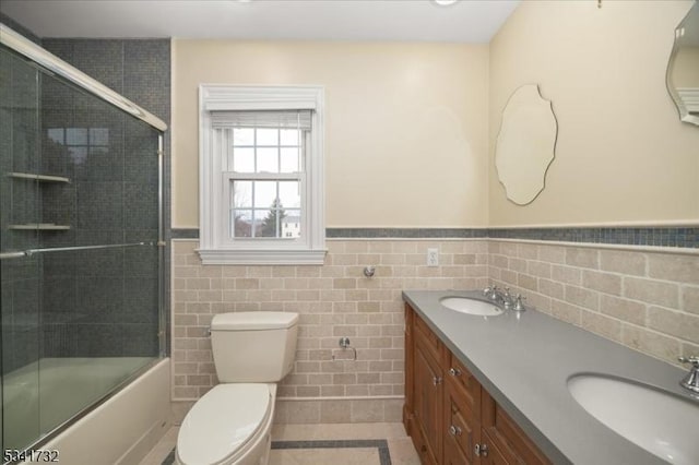 full bathroom featuring toilet, double vanity, a sink, and wainscoting