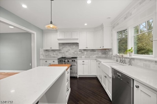 kitchen featuring dark wood finished floors, stainless steel appliances, light countertops, white cabinetry, and a sink